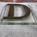 Metal letter D on glass plate