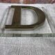 Metal letter D on glass plate