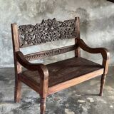 Small antique Indonesian bench in carved teak with plant and floral motifs.