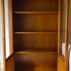 Straight molded clear wood cornice cabinet opening to two glass doors resting on  four sheath feet.