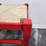 Red wooden stool with woven rush seat.