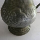 pewter pitcher with handle and bunch of grapes on the pot