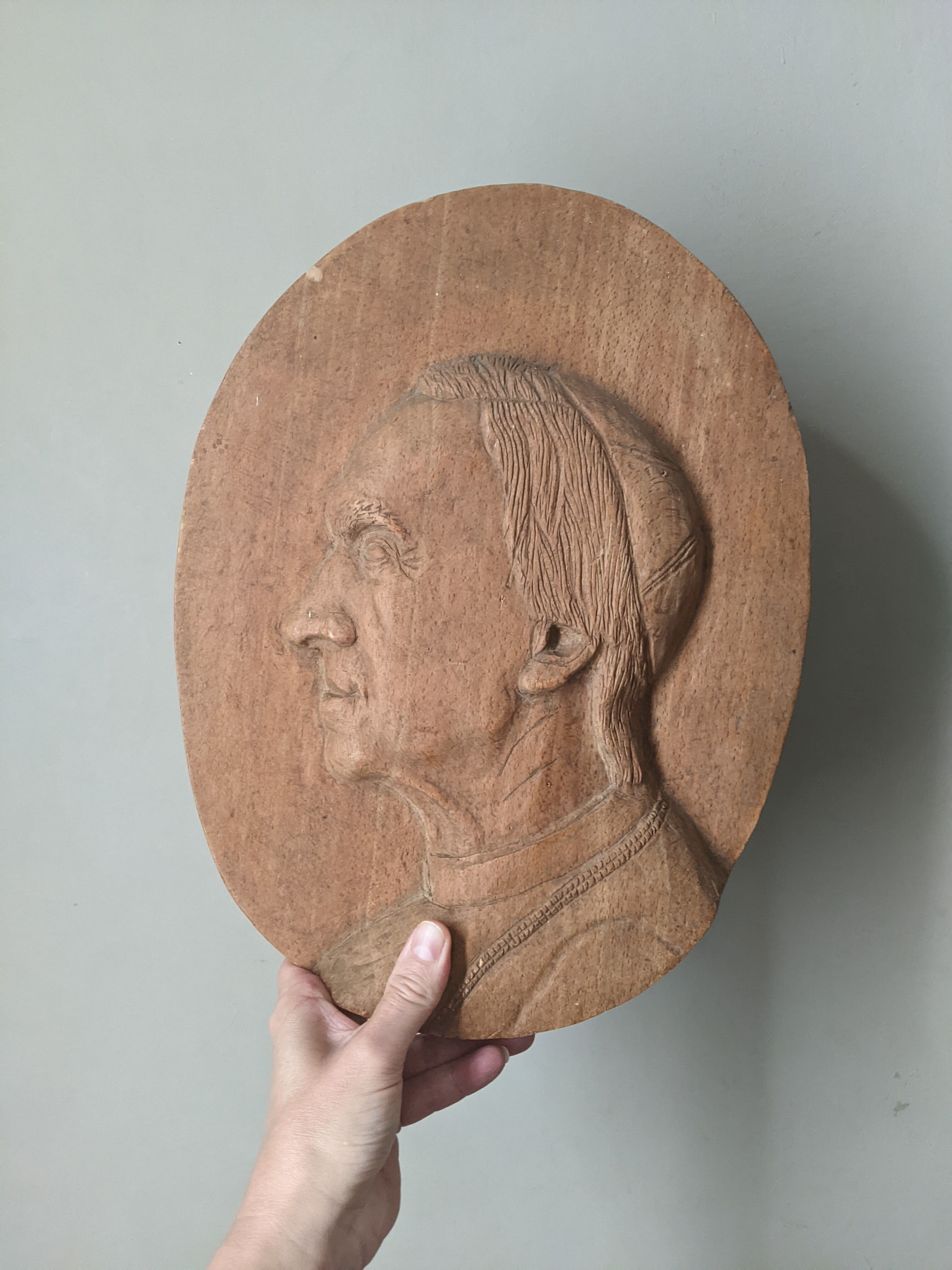 Oval wooden relief portrait of a cardinal.