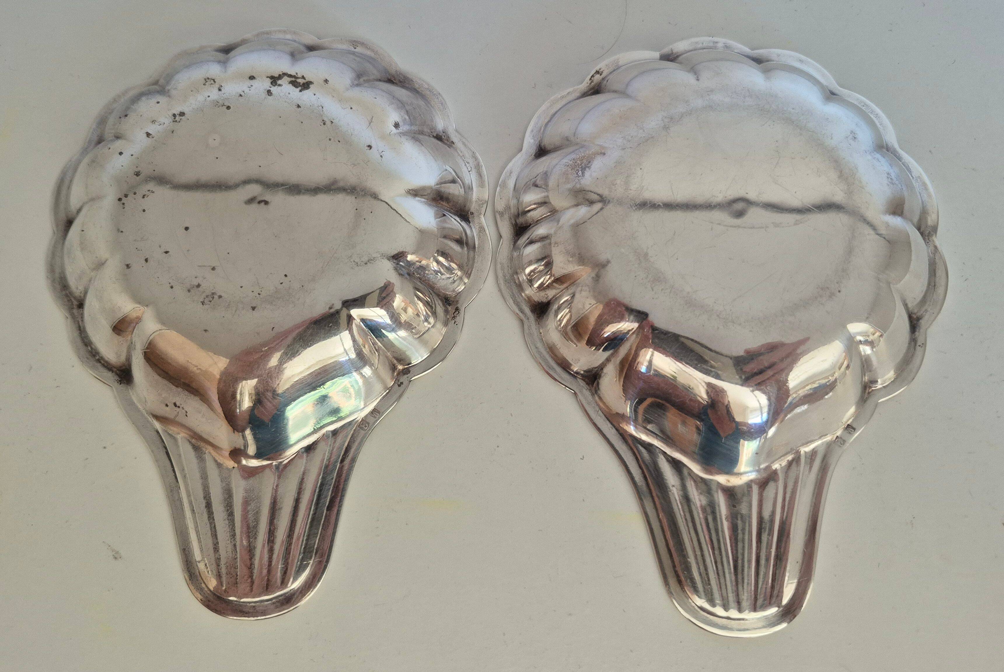 Silver-plated shell-shaped butter dishes, in the shape of a scallop shell.