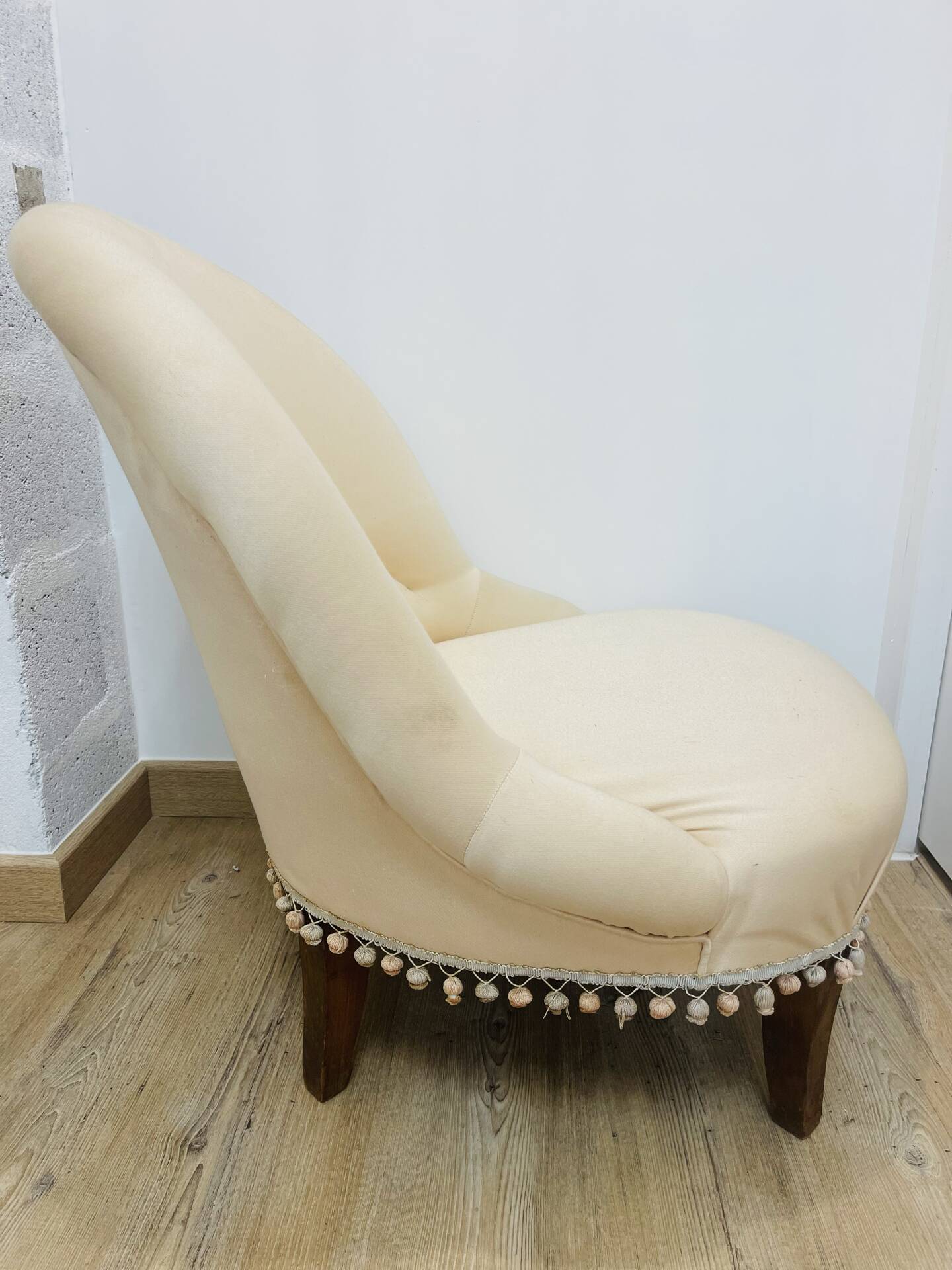 Pale pink upholstered armchair with wooden legs.