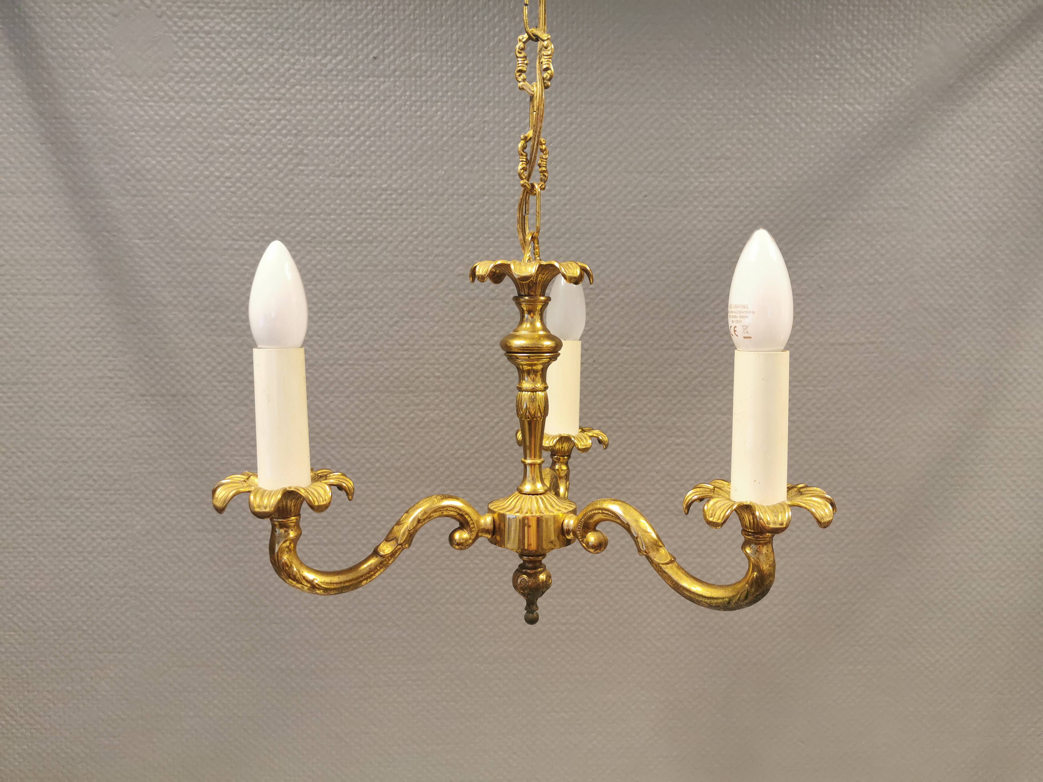 Older brass alloy chandelier with three light sources.