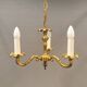 Older brass alloy chandelier with three light sources.