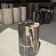Black petrified wood side table with beige stripes and a semicircular shape.