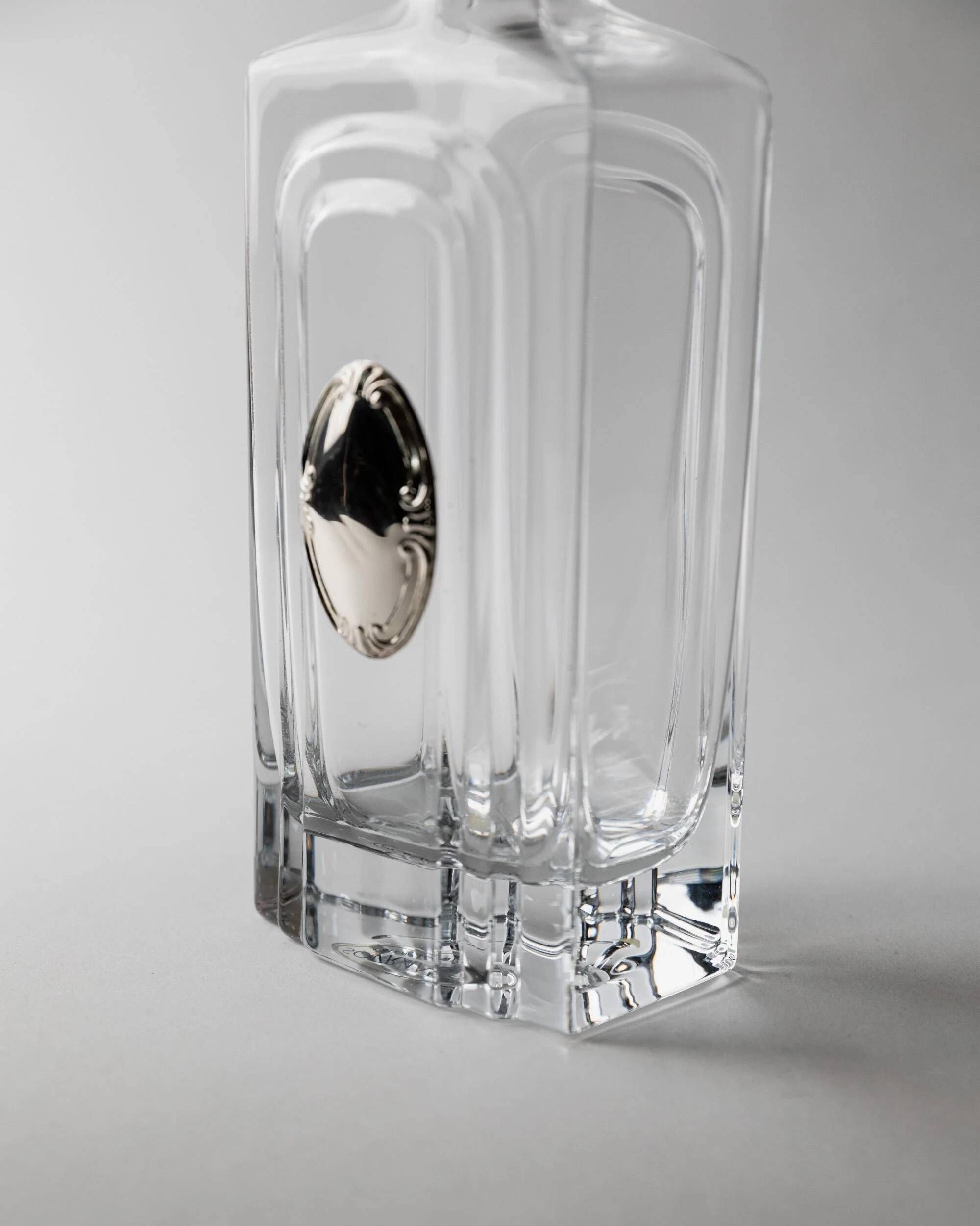 Vintage glass decanter from the 1980s, transparent glass with a silver plate and spherical stopper.