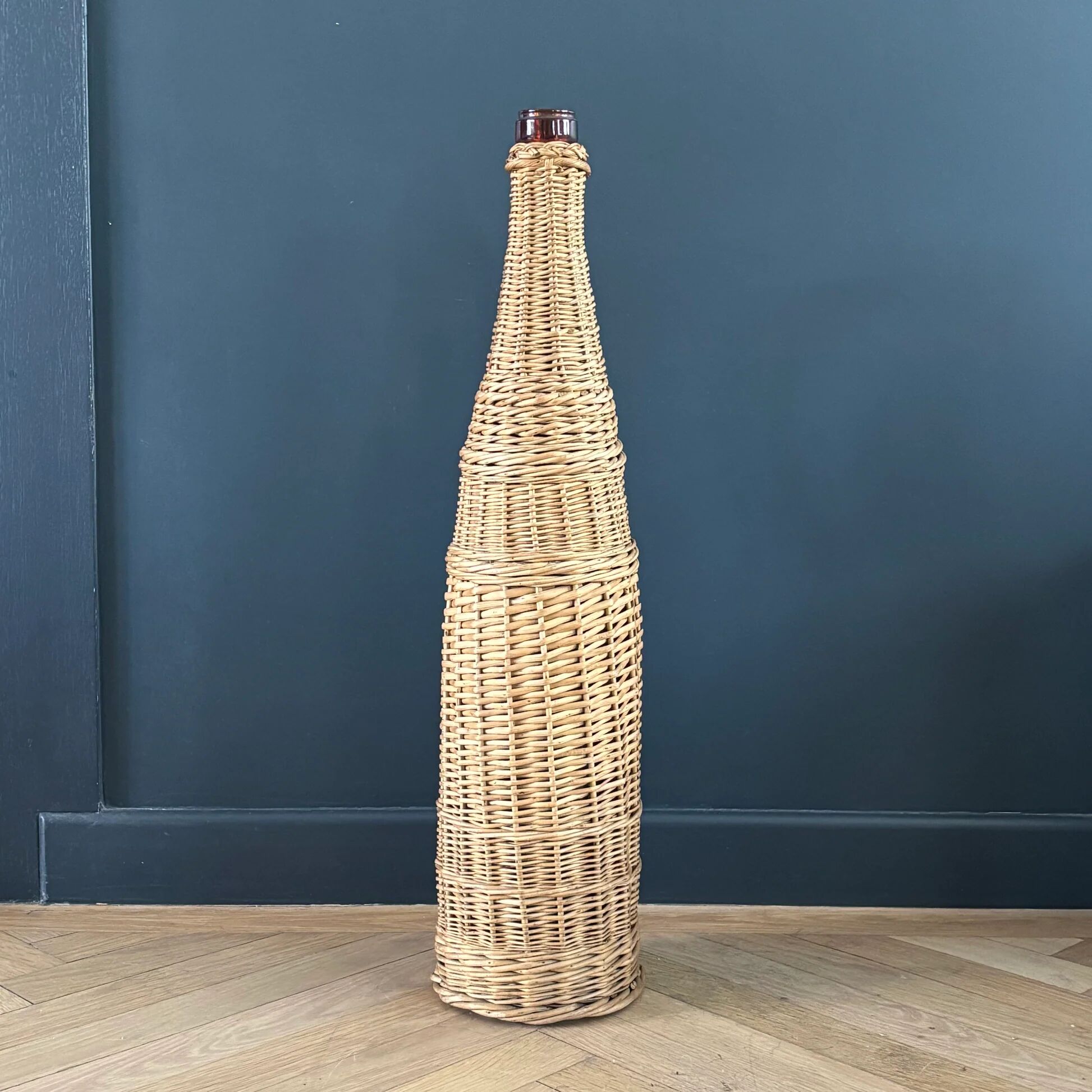 Amber glass bottle in its wicker handle basket.