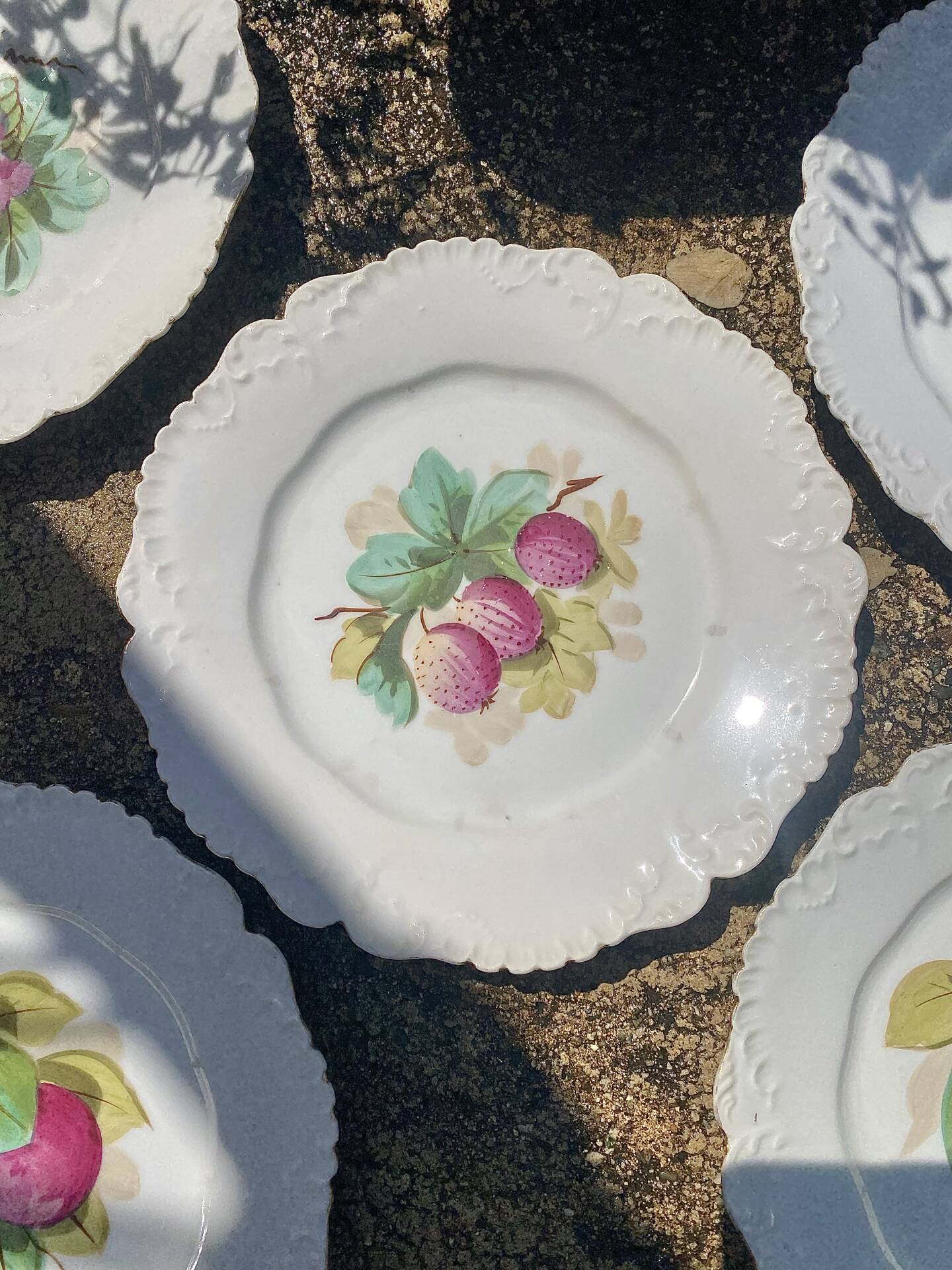 Antique plates from the late 19th century with scalloped edges and fruit decoration.