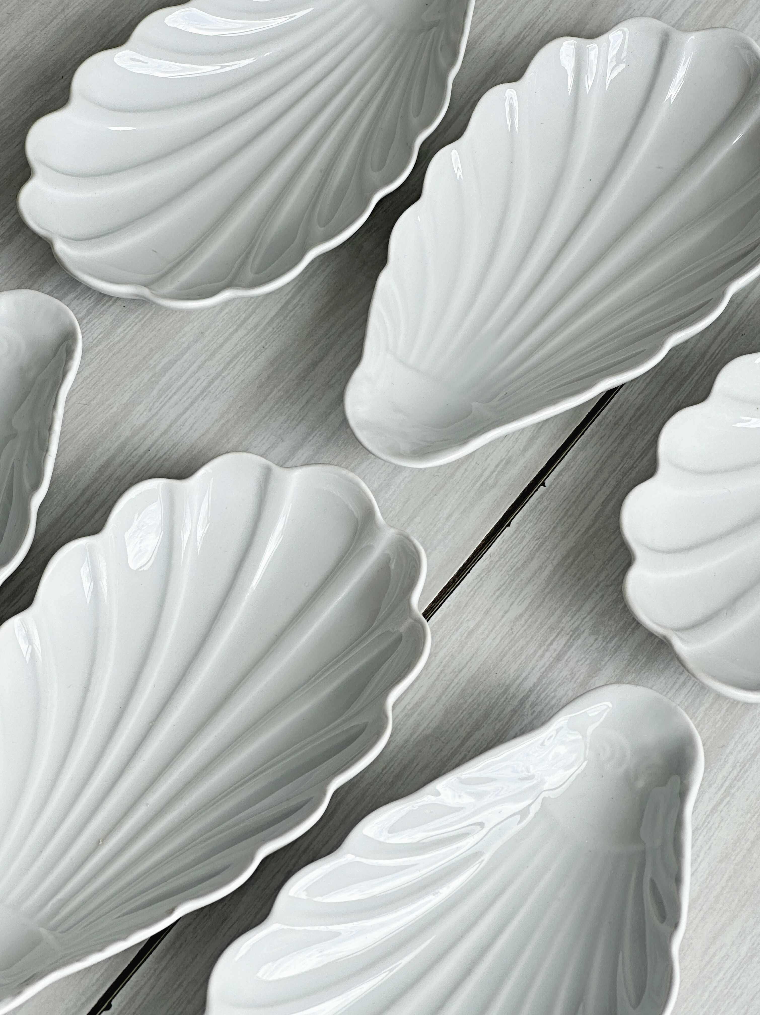 Set of white porcelain ramekins, ribbed shell shape.