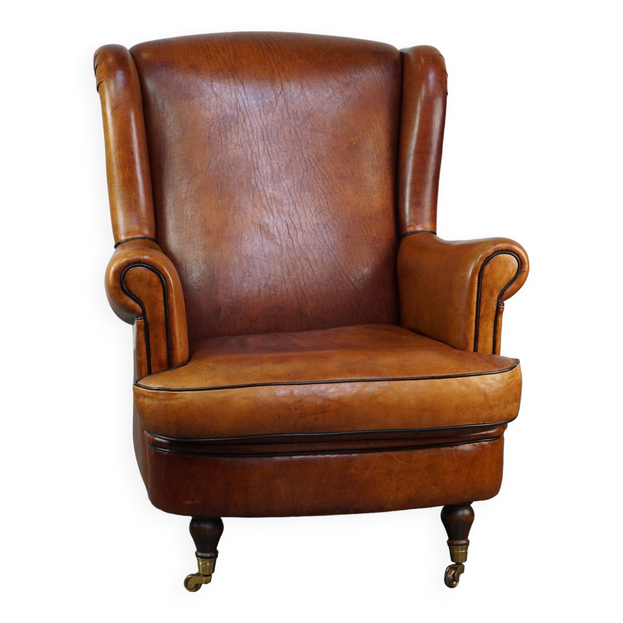 Subtle sheepskin wing chair in good condition on brass front wheels