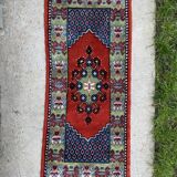 Vintage hand-knotted wool rug with polychrome decoration on a red, blue, green background 150 x 63 cm