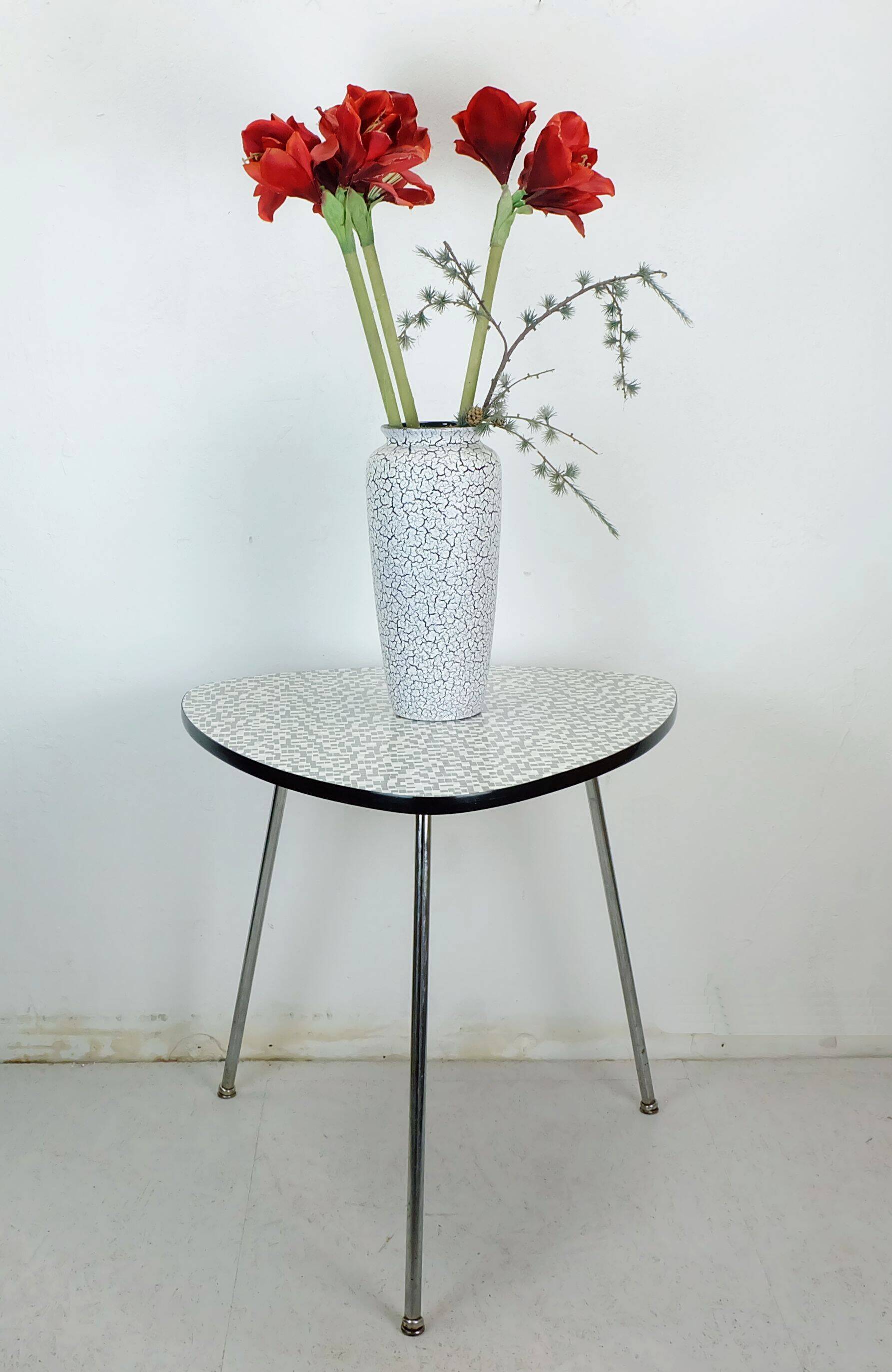 Table basse des années 1950 à trois pieds avec un plateau en formica et des pieds en chrome inclinés.