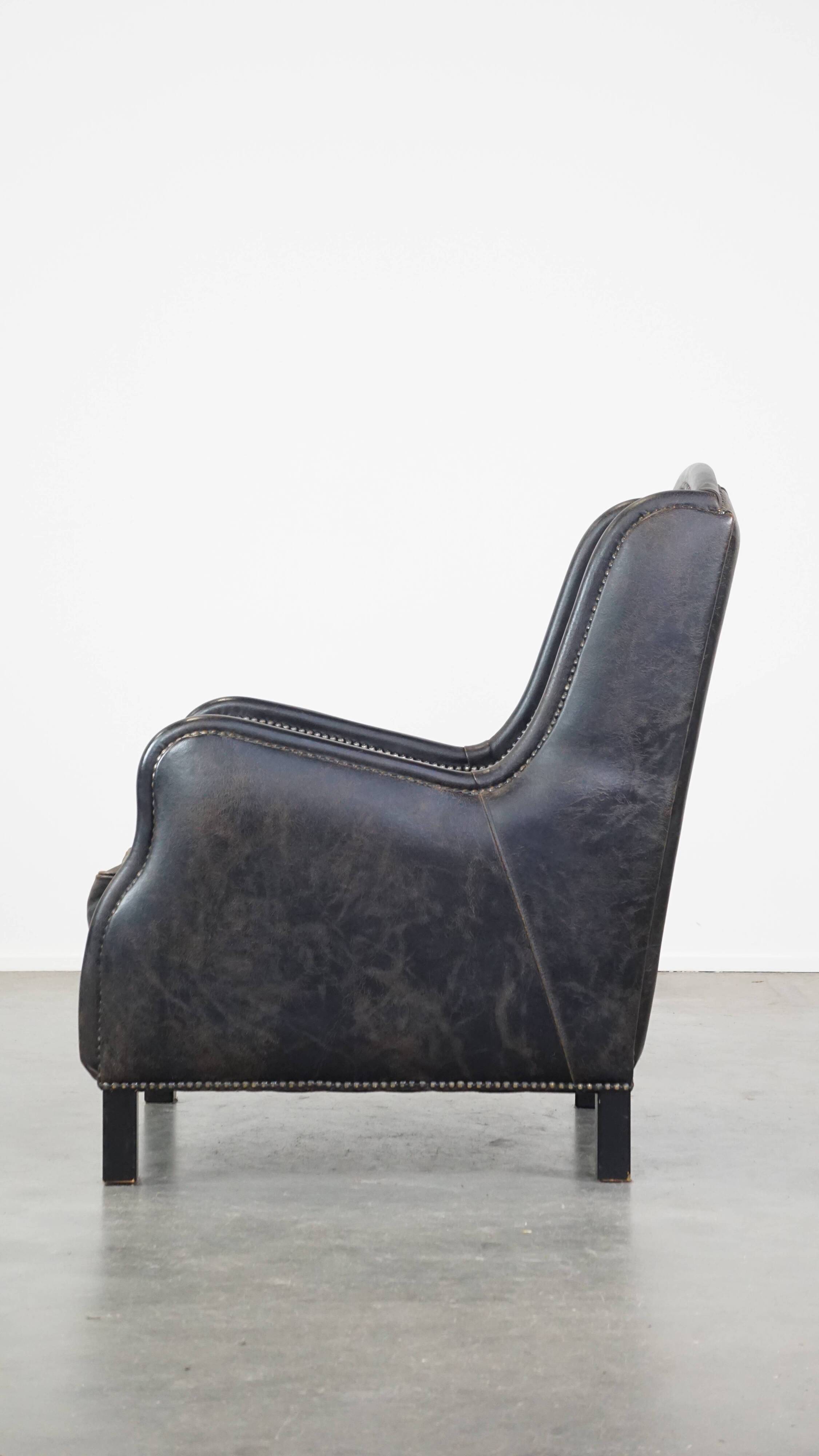 Black cow leather armchair in industrial style finished with decorative nails