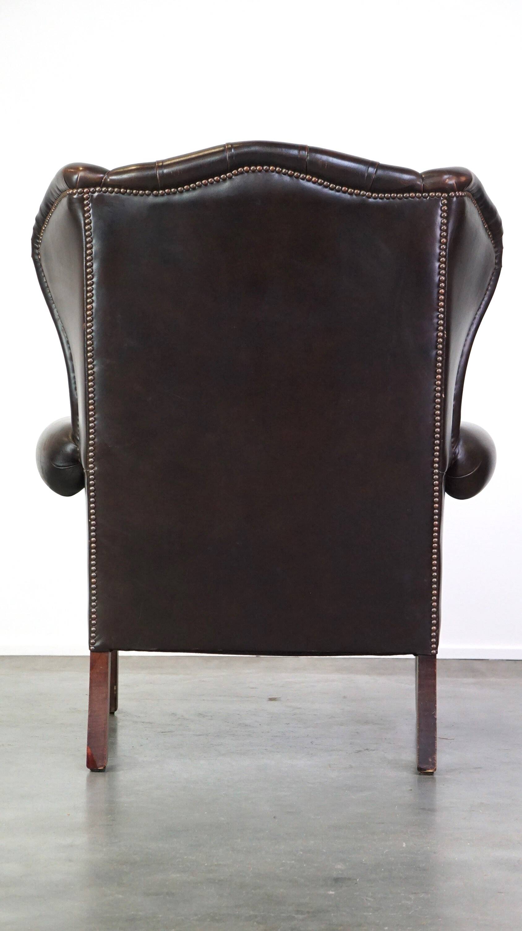 Chesterfield wing chair in dark brown leather with a luxurious appearance