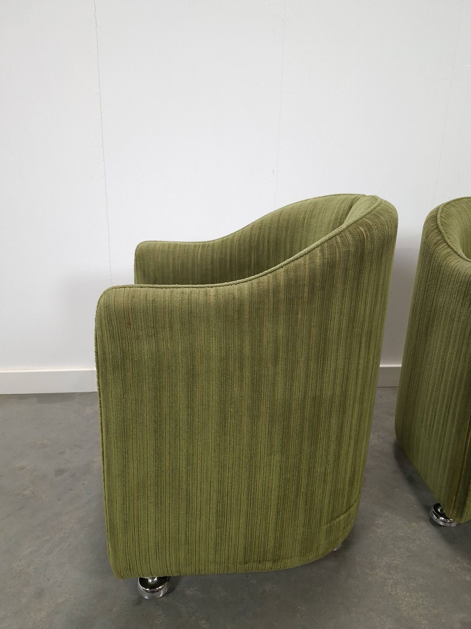 Chaises de cocktail vertes avec des roues chromées.