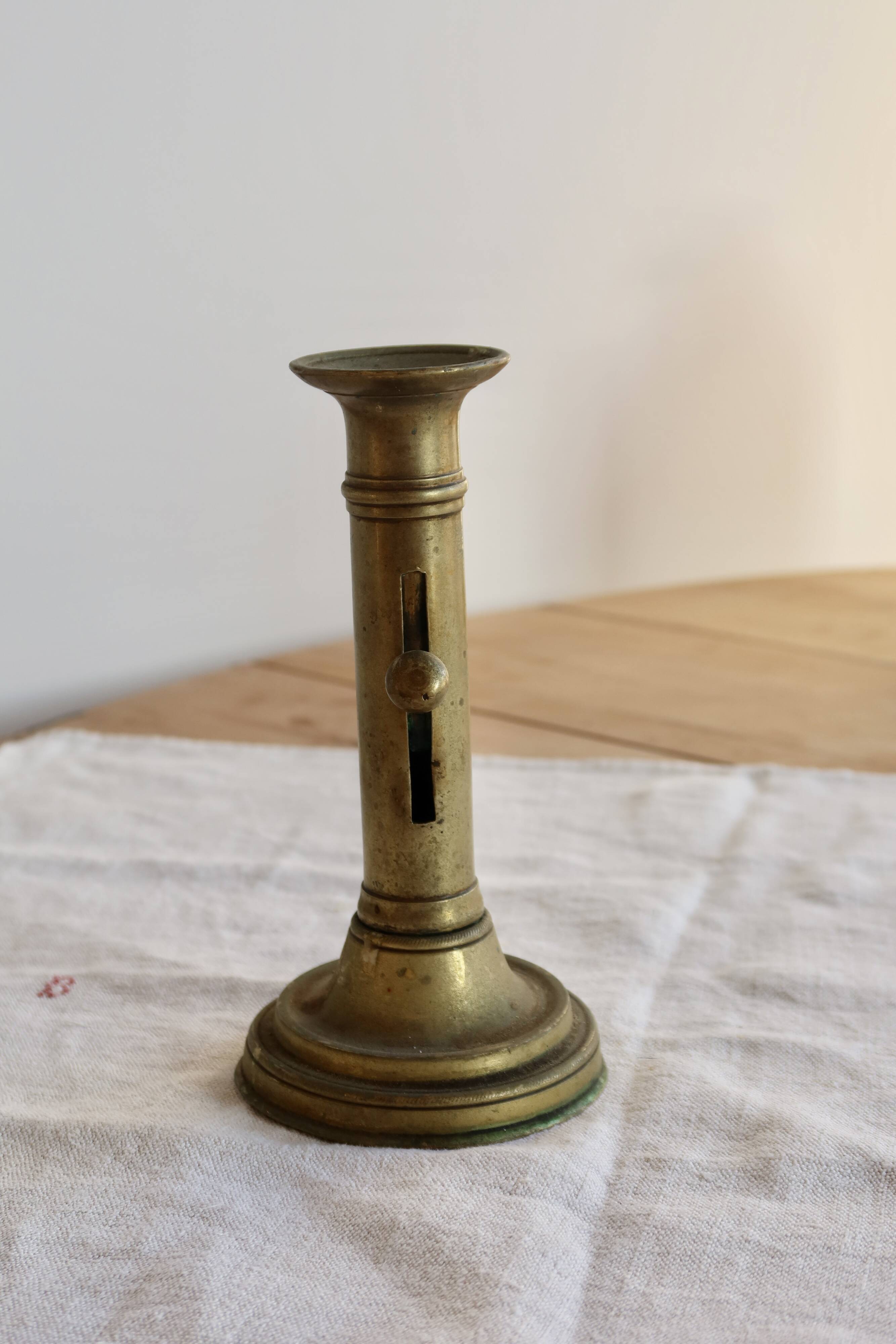 Antique brass candlestick with a push button.