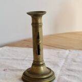 Antique brass candlestick with a push button.
