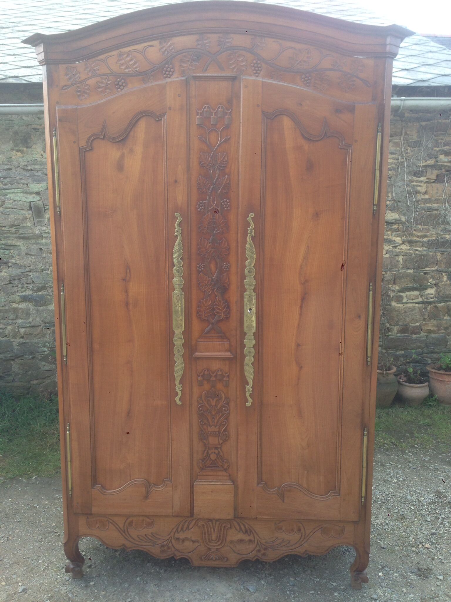 Armoire Louis XV Nantaise sculptée à grappes de raisin, chapeau de gendarme en cerisier fin 19eme.