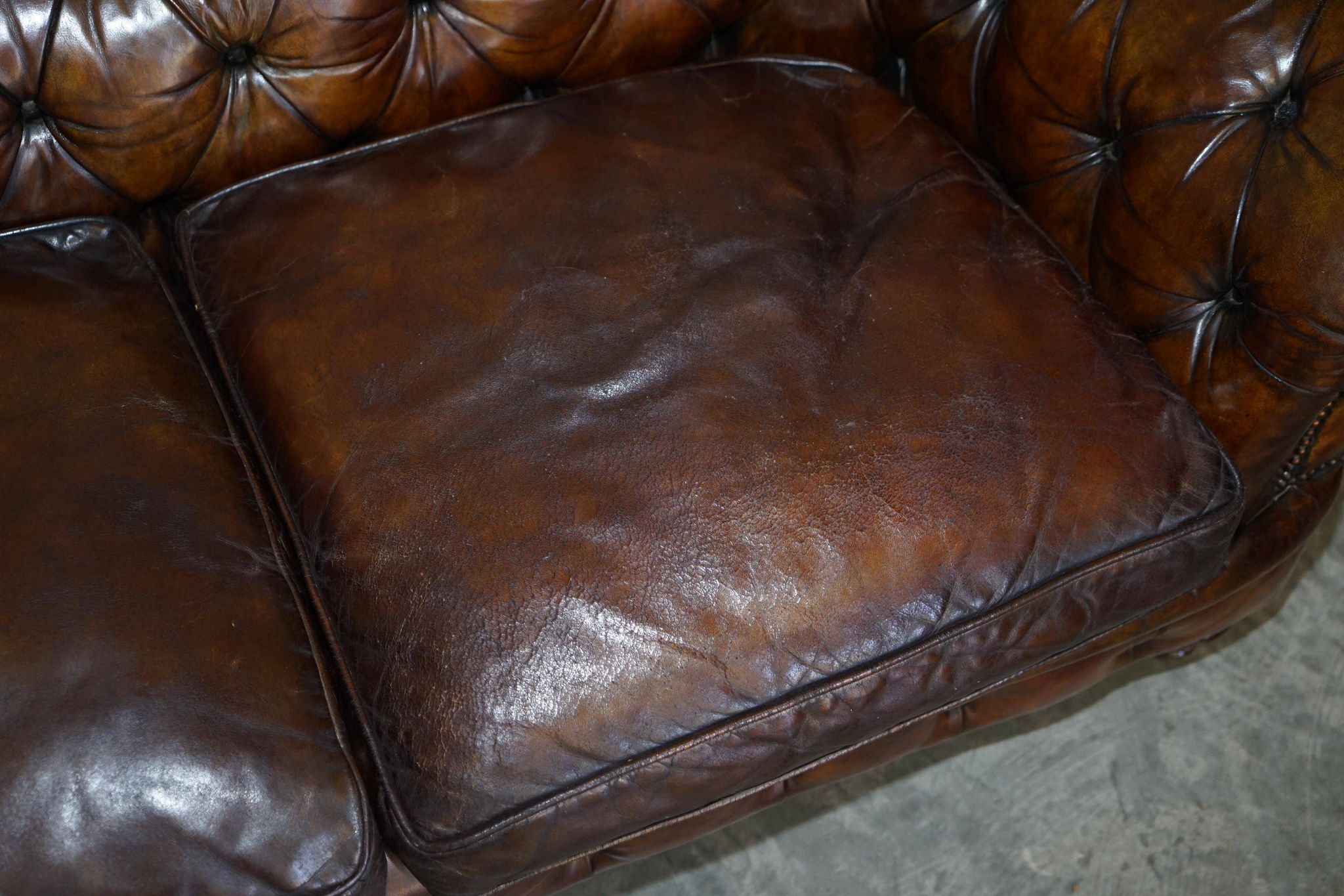 Victorian Chesterfield leather upholstered canapé with feather cushions.