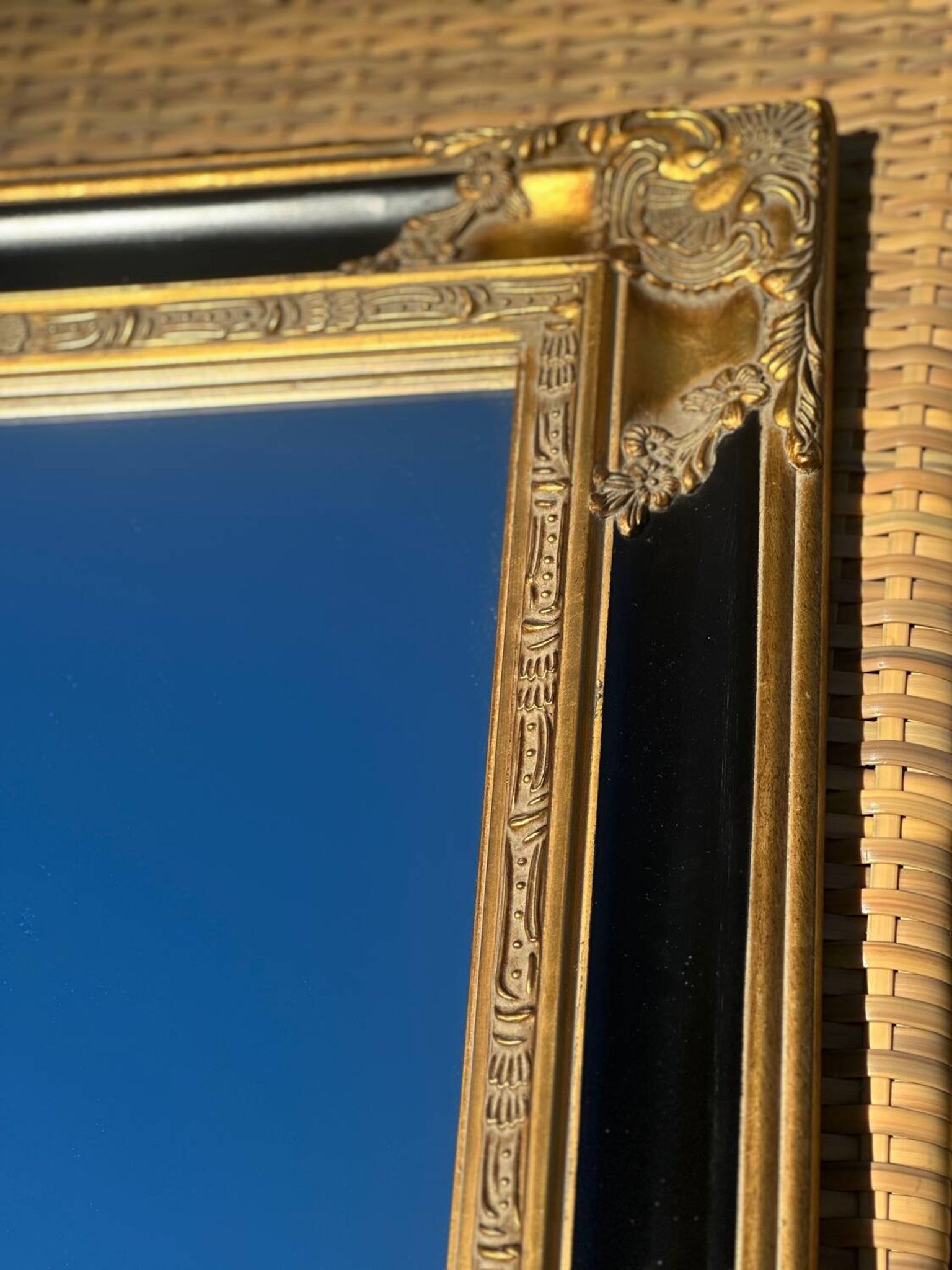 Miroir Baroque en bois doré sur fond noir.
