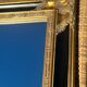 Baroque mirror in gilded wood on a black background.
