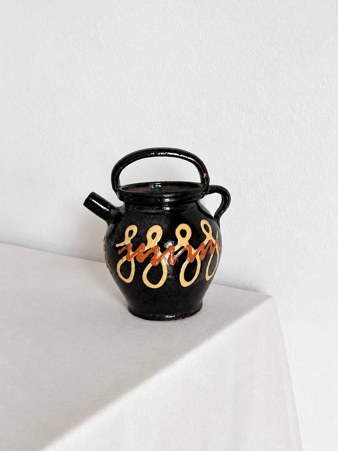 Old vase in glossy black ceramic, vintage exterior decoration.