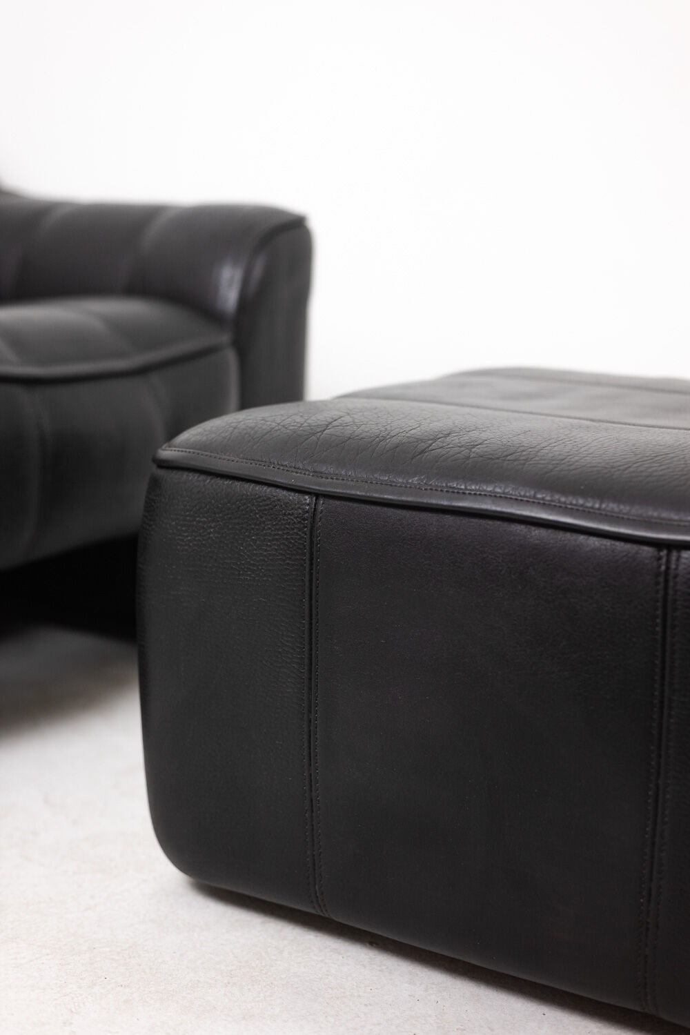 Maison De Sede. Armchair and its ottoman in black leather. 1970s.
