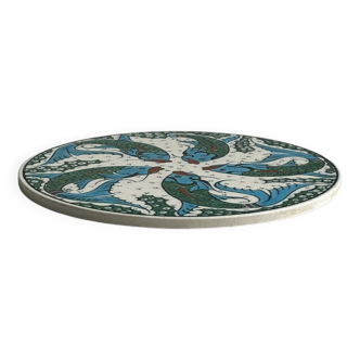 Ceramic trivet with colorful stylized fish patterns.