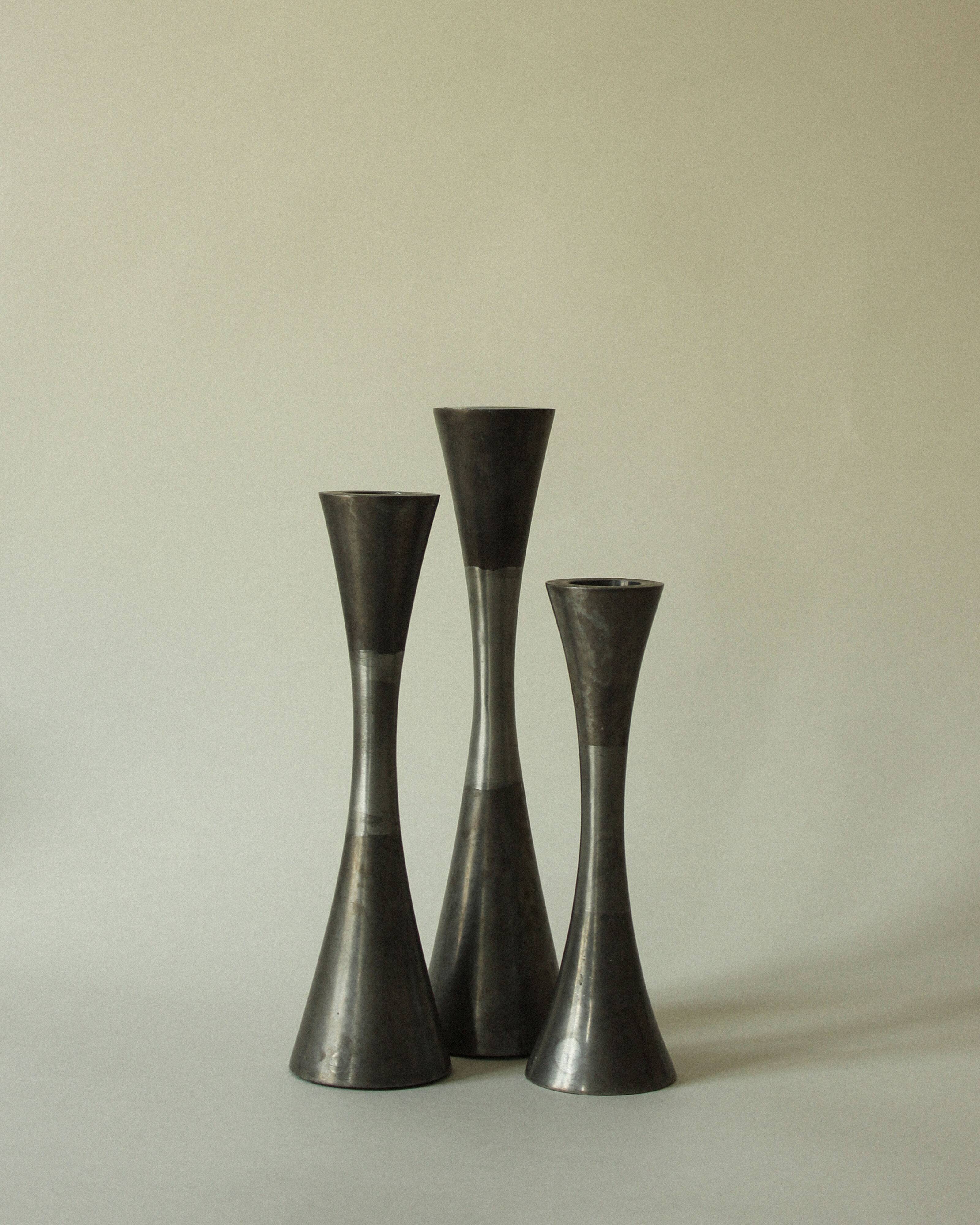 Set of three diabolo-shaped candle holders made of cast steel.