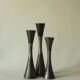 Set of three diabolo-shaped candle holders made of cast steel.