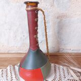 Amber bottle covered in colored leather with handle surrounded by wire, vintage