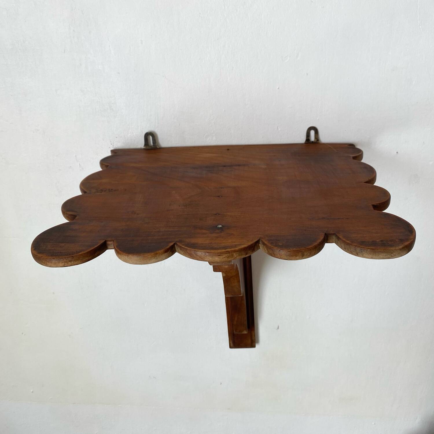 Antique wall shelf with a scalloped edge.