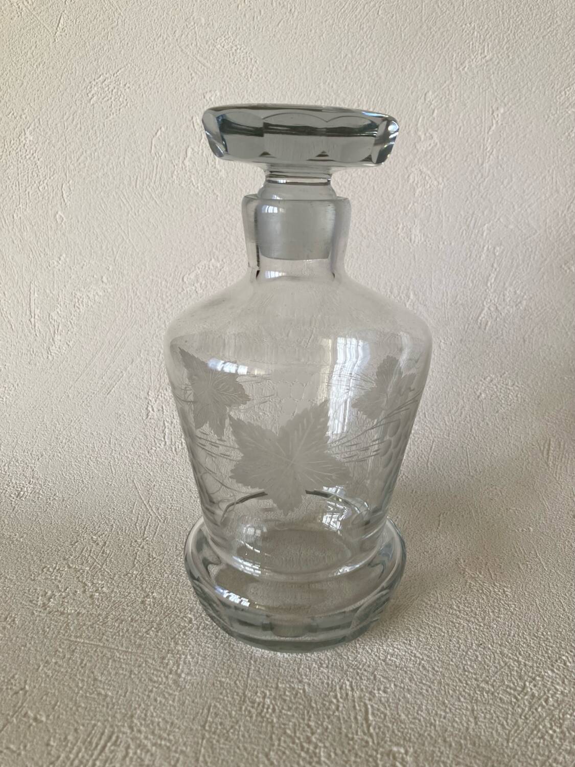 Small carafe in blown cut glass with engraved decoration of vine leaves and grapes, threaded stopper