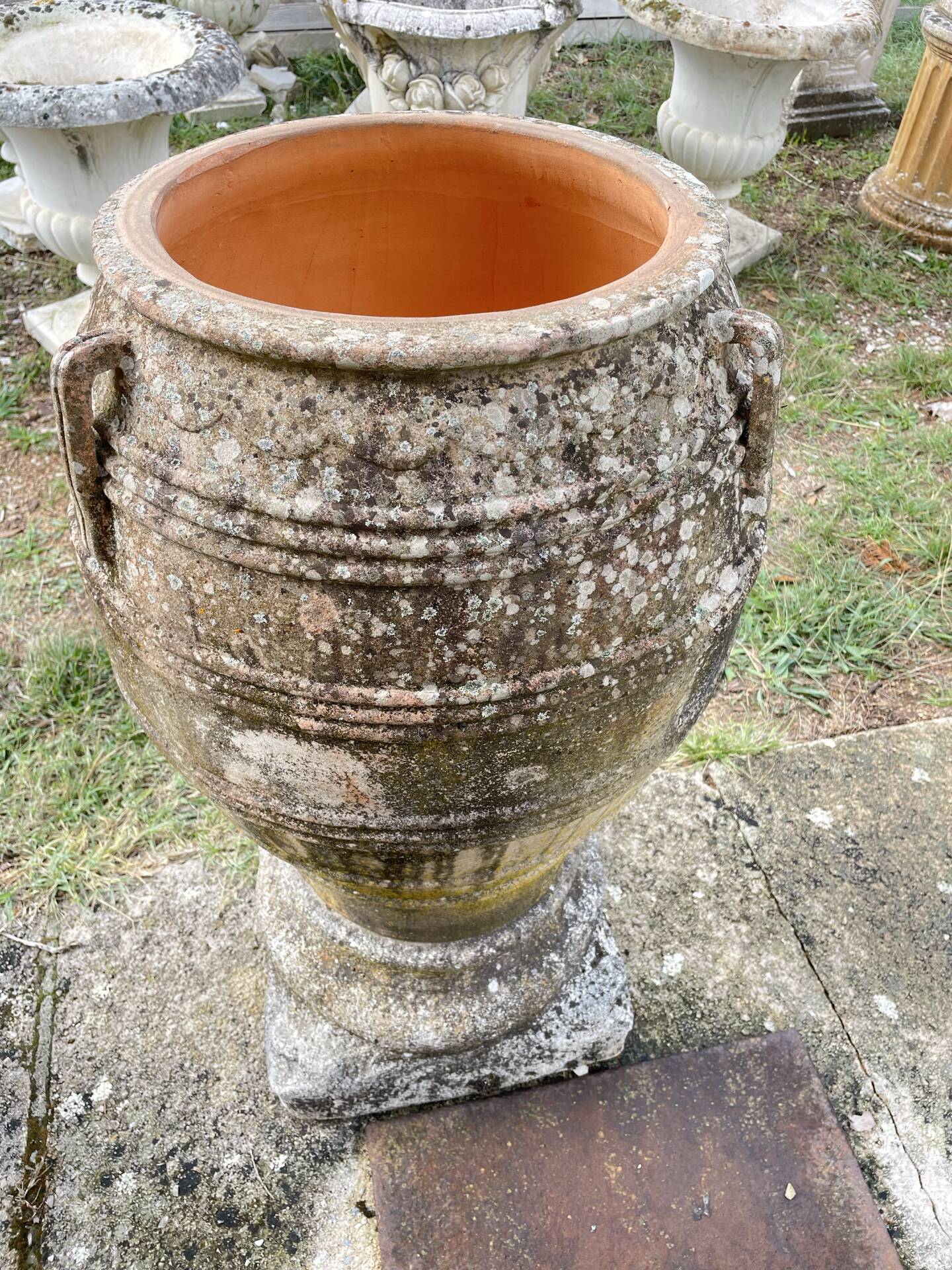 Large Cretan jar in terracotta with three handles on a stone base.