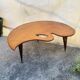 Mid-century coffee table with a palette shape and splayed legs.
