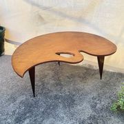Mid-century coffee table with a palette shape and splayed legs.