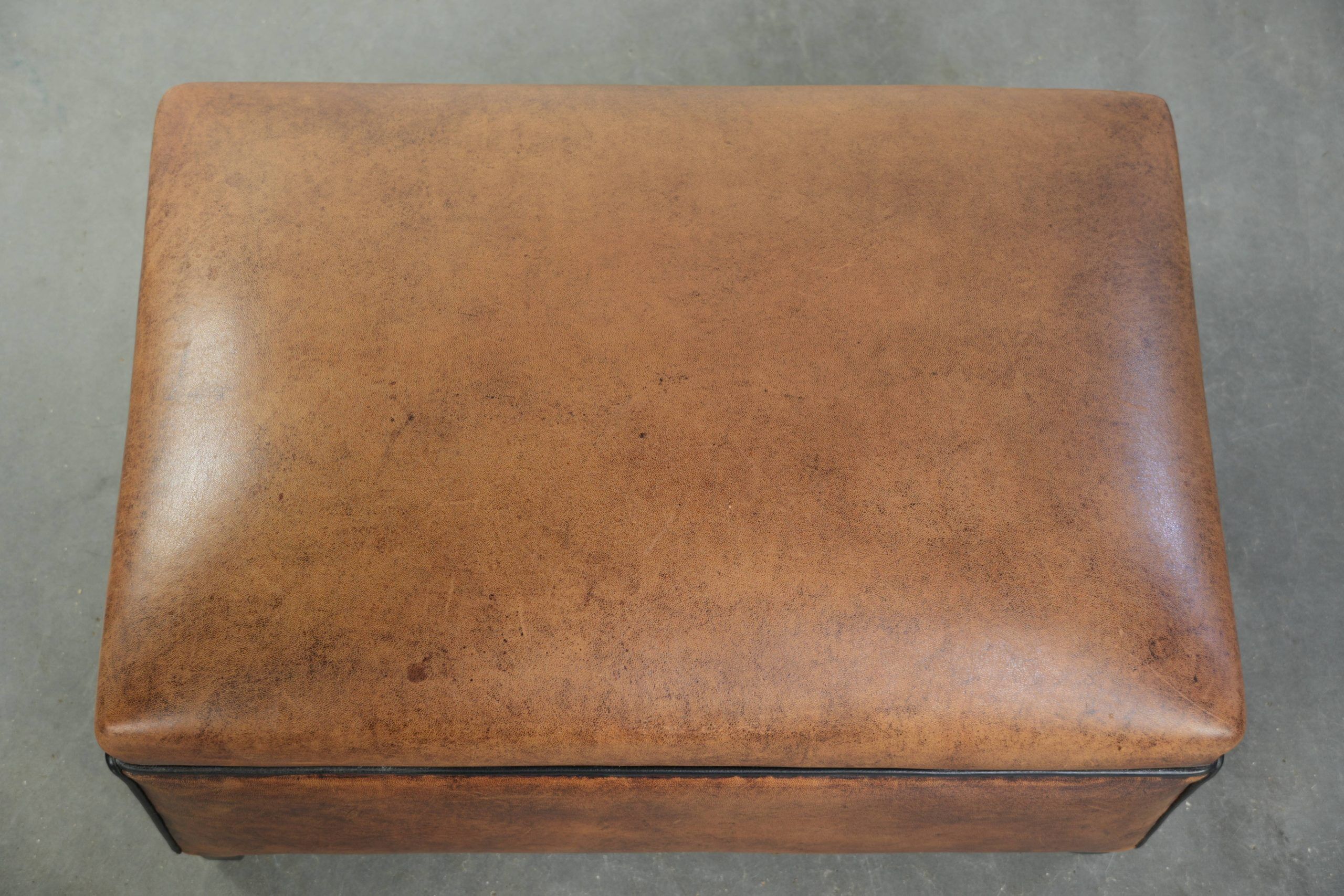 Characterful sheepskin footstool/ottoman finished with black piping