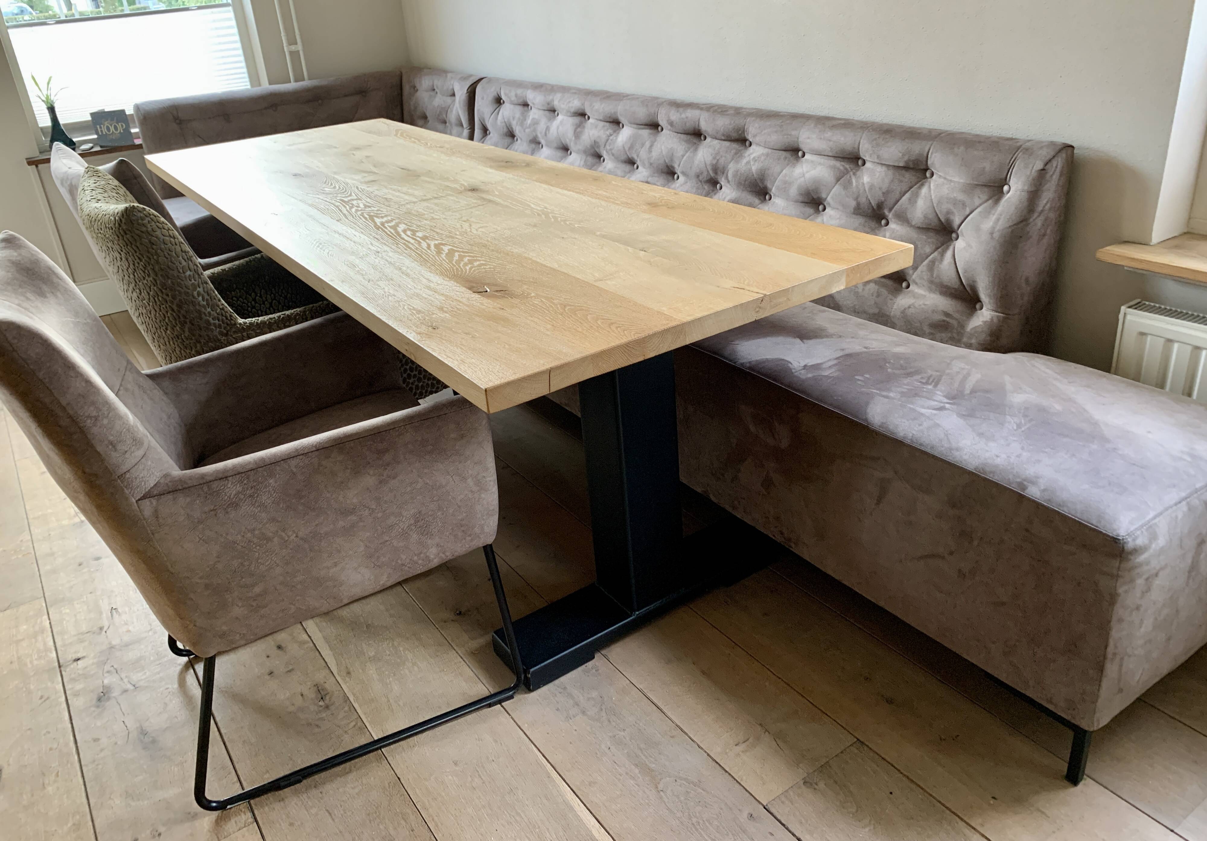 Dining table made of wood with three leather seats and a long leather sofa.