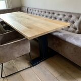 Dining table made of wood with three leather seats and a long leather sofa.