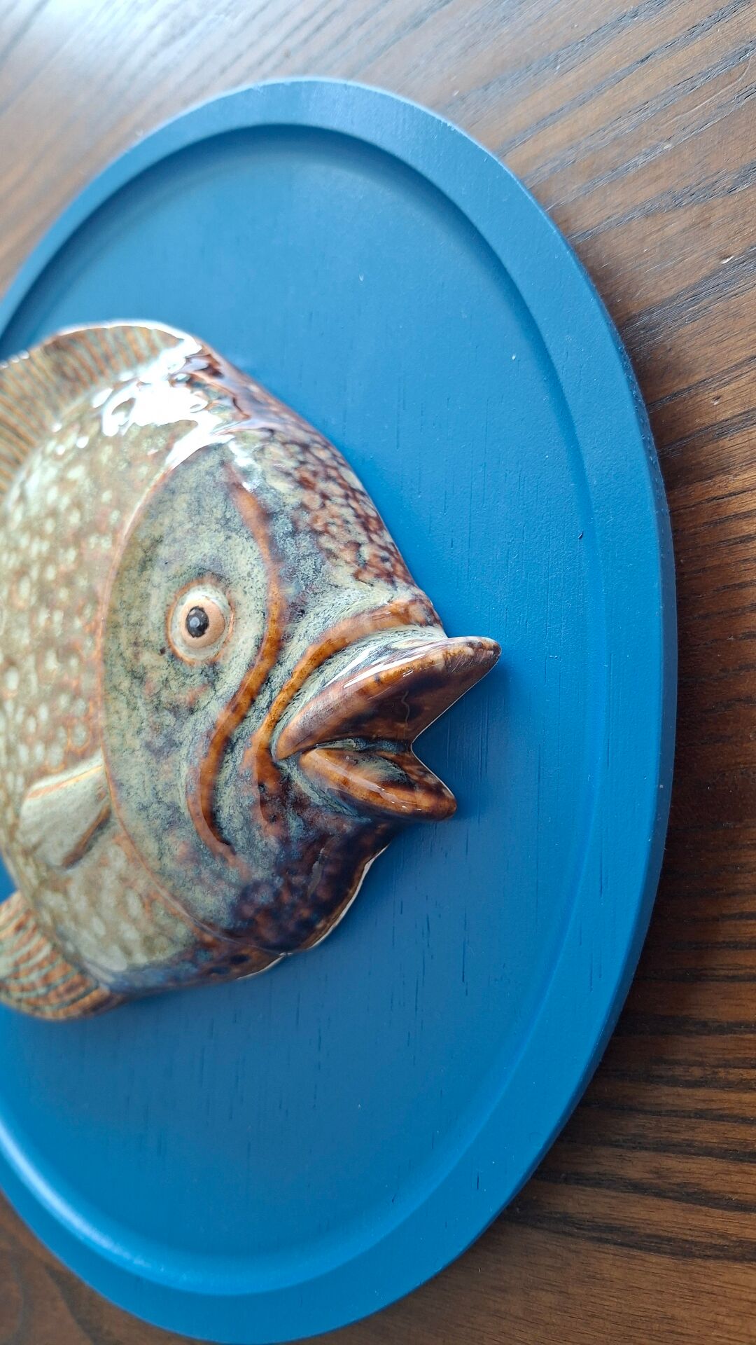 Vallauris ceramic wall sculpture of a relief fish on a blue plaque.