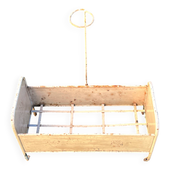 Metal doll bed with a draped curtain. Antique toy from the early 20th century.