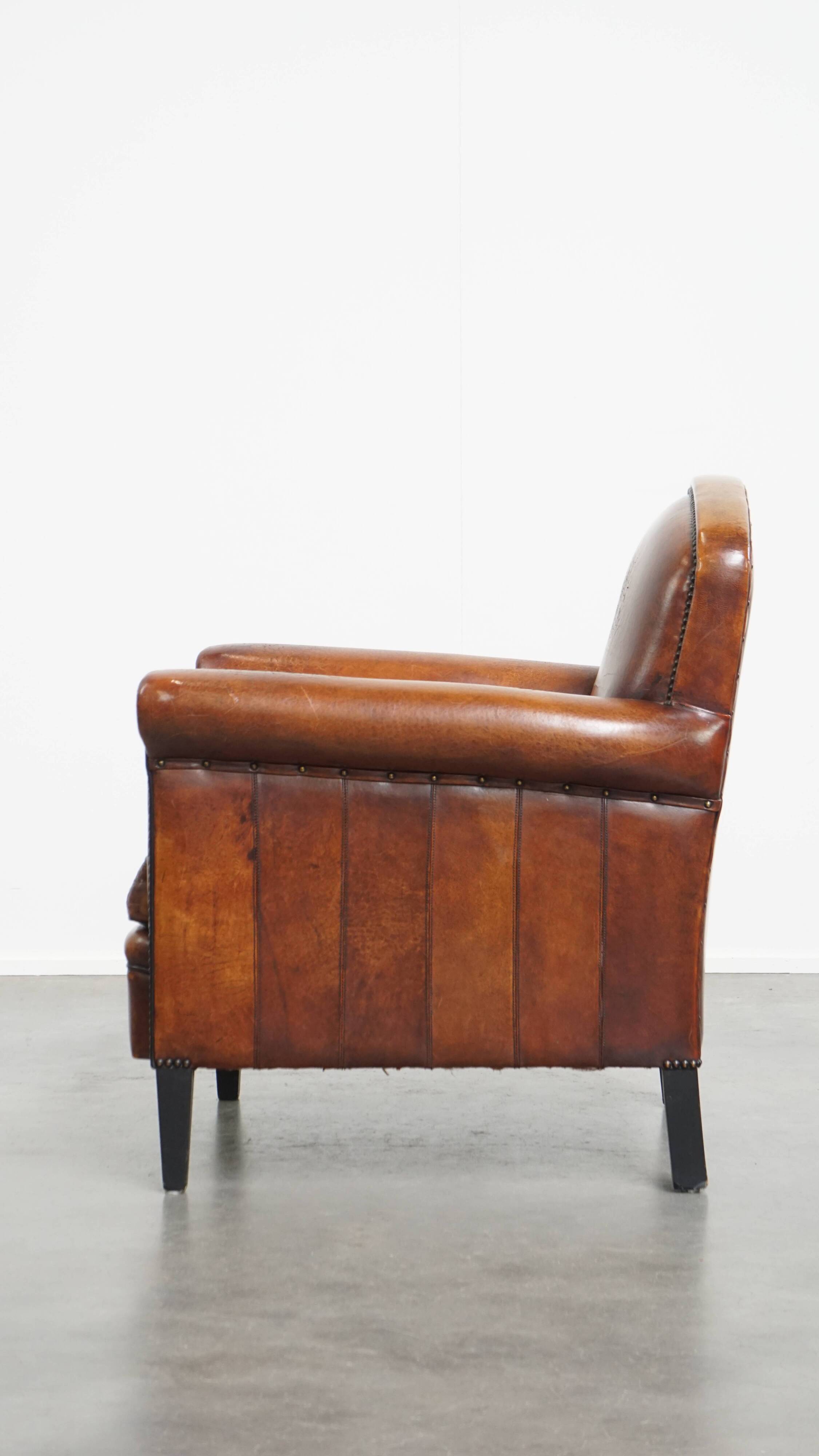 Sheepskin leather armchair in a cognac color with black piping