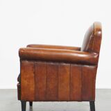 Sheepskin leather armchair in a cognac color with black piping
