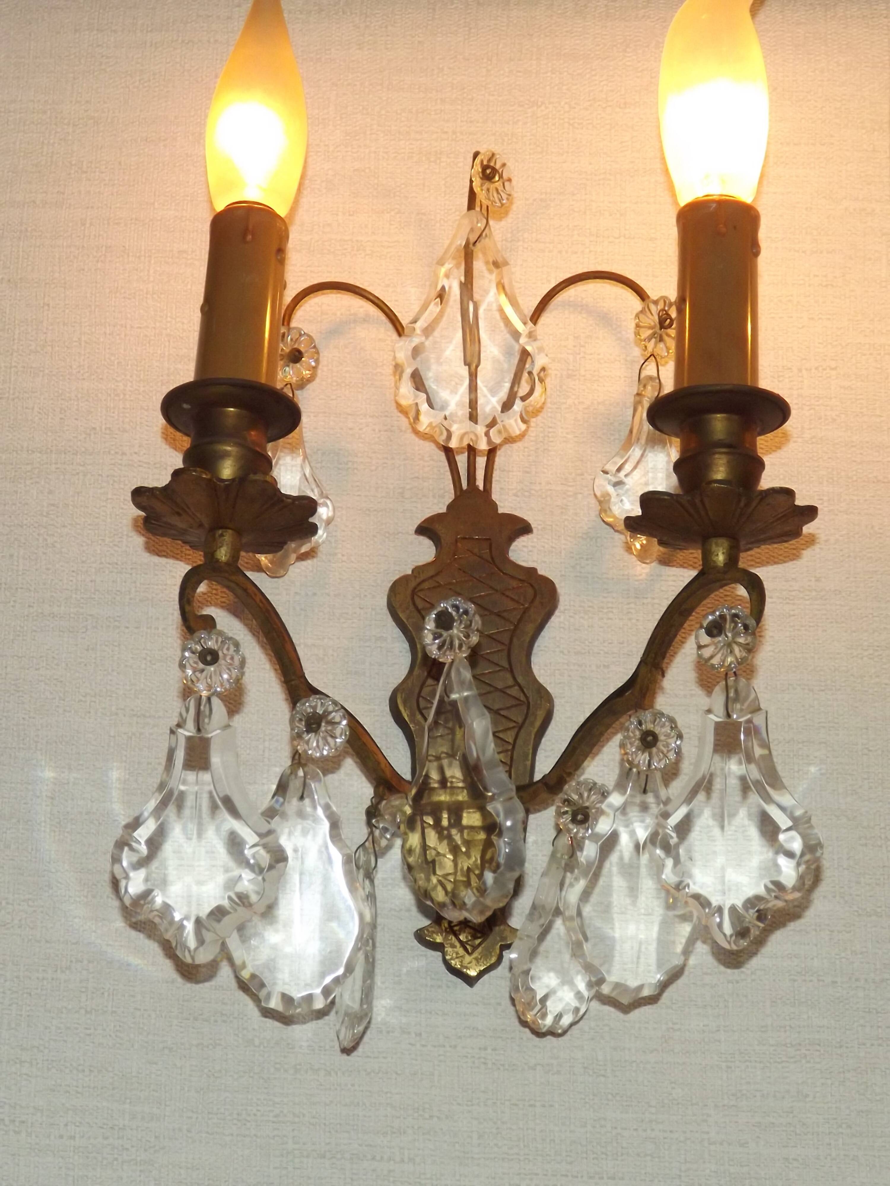 Pair of French antique brass double wall lights with assorted crystals.