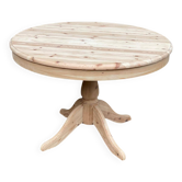 Renovated round extendable Scandinavian dining table in raw wood with a central leg.