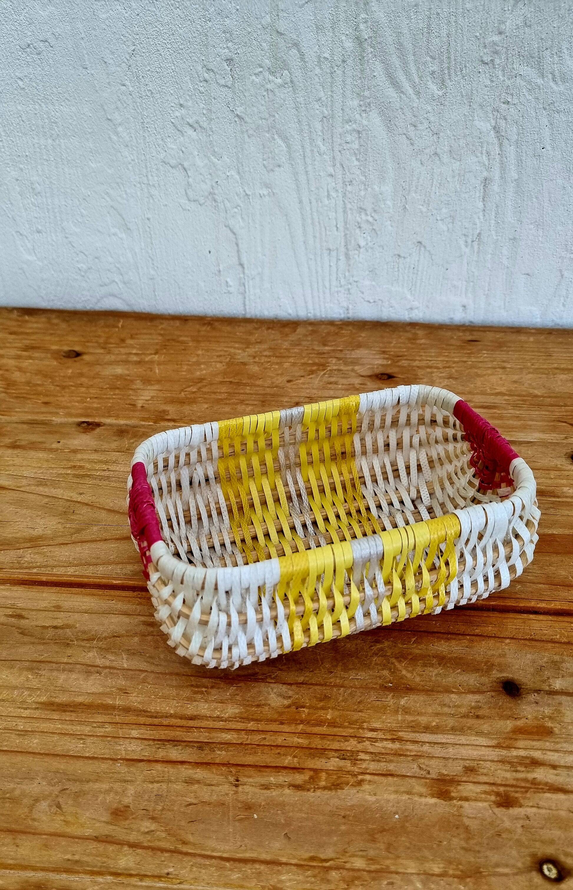 Vintage woven basket in yellow, white, and pink plastic.