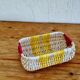 Vintage woven basket in yellow, white, and pink plastic.